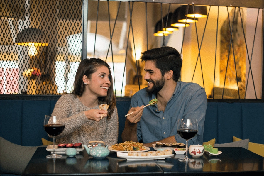 couple enjoying dinner together and enjoying small plates and glasses of red wine